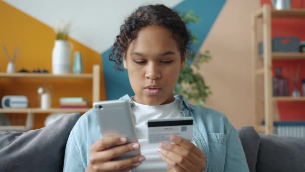 Afro-americano mulher fazendo pagamento sem dinheiro on-line usando cartão de crédito e smartphone — Vídeo de Stock
