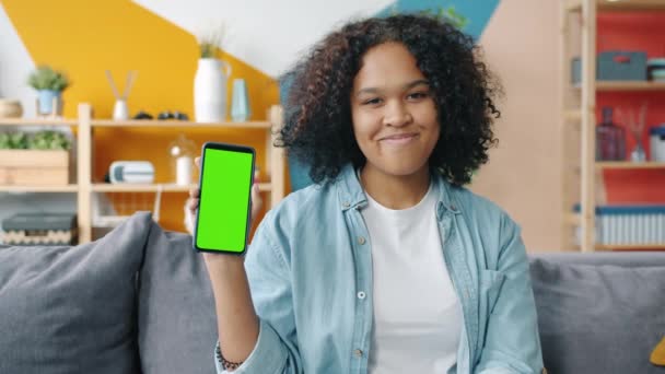 Portrait of African American girl holding green screen smartphone looking at camera — 비디오