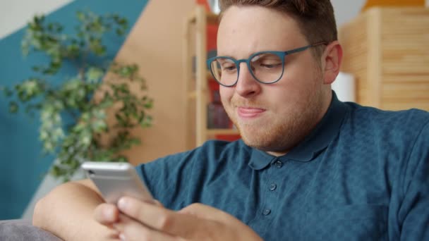 Cheerful guy using smartphone touching screen enjoying social media at home — 비디오