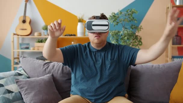 Gut aussehender Mann, der Spaß mit Virtual-Reality-Brille hat, die Hände bewegt — Stockvideo