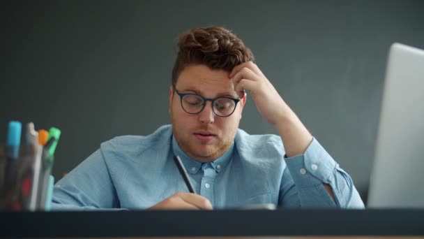 Tipo agotado escribiendo tomando notas sintiéndose cansado en la oficina sobre fondo gris — Vídeos de Stock