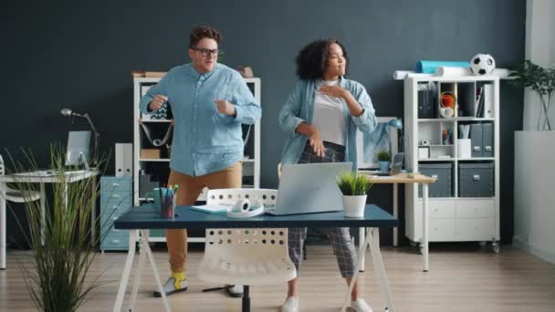 Gemengd ras kantoor werknemers meisje en jongen met plezier samen dansen genieten van muziek — Stockvideo