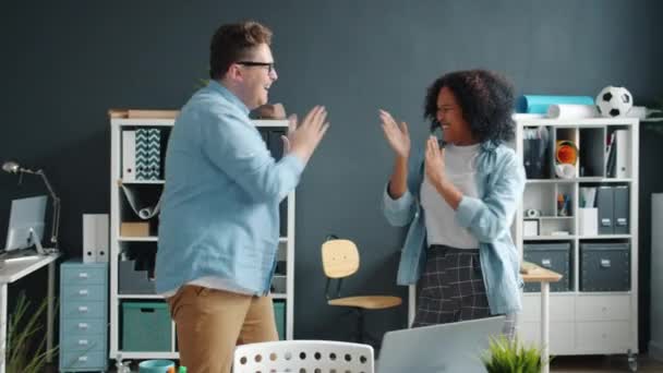 Afro-amerikansk dam och kaukasisk man som dansar klappar händerna och har roligt på kontoret — Stockvideo
