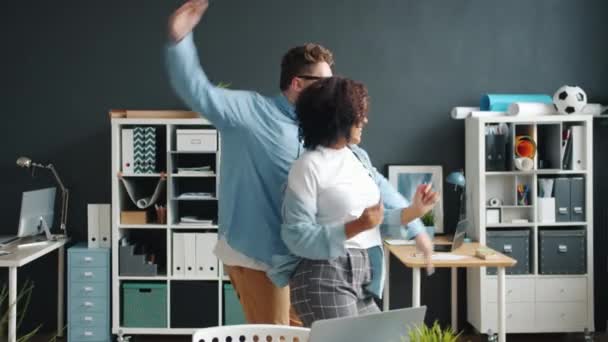 Joven alegre hombre y mujer bailando en la oficina divirtiéndose juntos en el trabajo — Vídeos de Stock