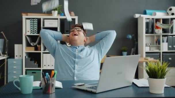 Slow motion av massor av pengar faller på stilig kille på kontoret sitter vid skrivbordet — Stockvideo