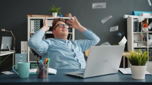 Empreendedor relaxante na cadeira no escritório, enquanto notas de dinheiro caindo de cima — Vídeo de Stock