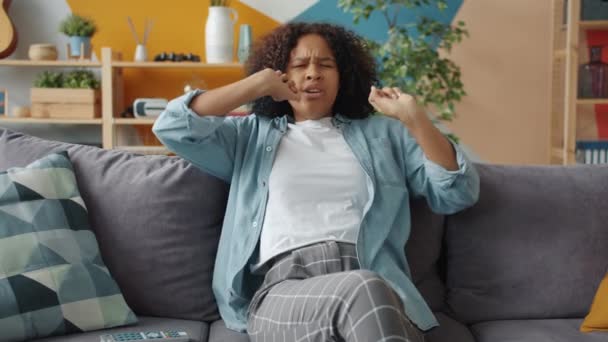 Спящая афроамериканка зевает, вытянув руки, просыпаясь после сна дома — стоковое видео