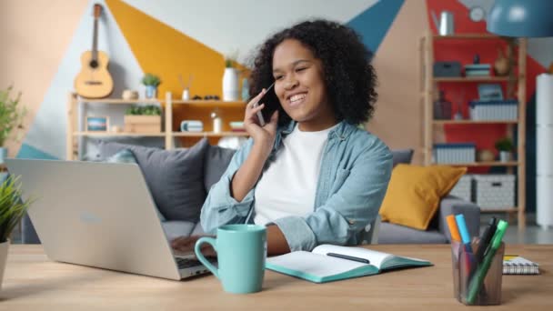 Joyeux jeune femme parlant sur téléphone mobile souriant travailler avec ordinateur portable à la maison — Video