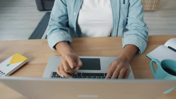 Alegre chica afroamericana disfrutando de contenido de Internet utilizando el ordenador portátil en casa sonriendo — Vídeos de Stock