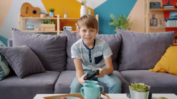 Porträt eines glücklichen Jungen, der allein Videospiel spielt und zu Hause auf einer bequemen Couch sitzt — Stockvideo