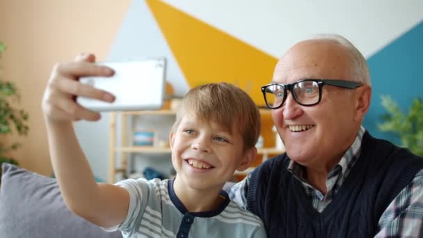 Pessoas alegres velho homem e menino tomando selfie em casa posando sorrindo usando smartphone — Vídeo de Stock