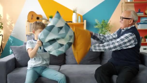 Gente juguetona anciano y lindo chico disfrutando de la pelea de almohadas divertirse en casa — Vídeos de Stock