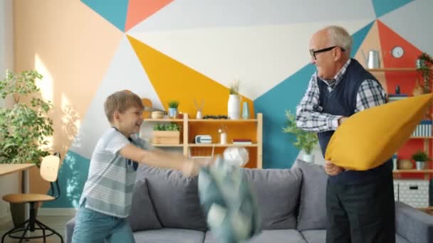 Mouvement lent de la famille heureuse homme âgé et garçon riant oreillers de combat — Video