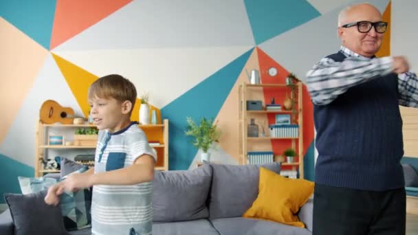 Odchylony staruszek i mały chłopiec wykonujący ćwiczenia fizyczne w mieszkaniu — Wideo stockowe