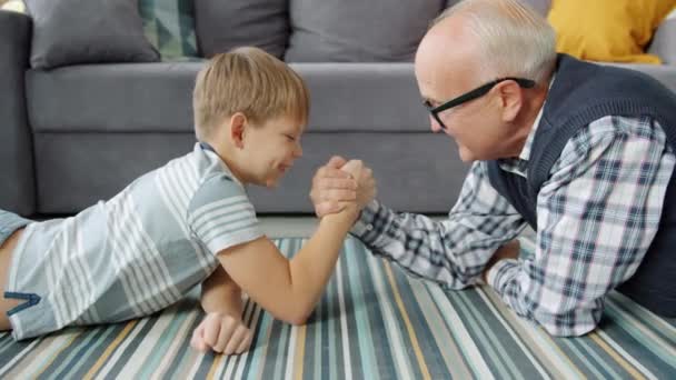 Hombre mayor y niño pequeño practicando el descanso de brazos en casa disfrutando de la actividad — Vídeos de Stock