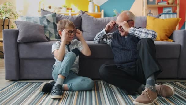 Retrato del abuelo y el nieto poniéndose anteojos sonriendo divirtiéndose en casa — Vídeos de Stock