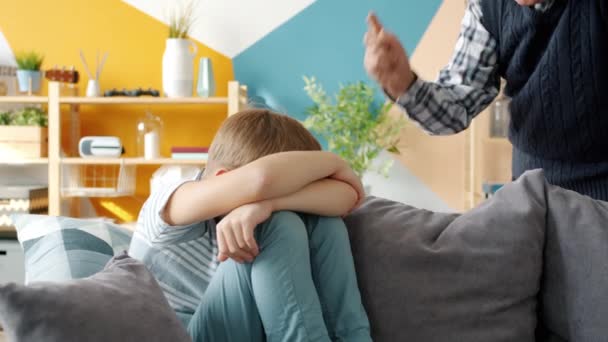 Avô estrito punir o pequeno menino abanando o dedo na criança sentada no sofá chorando — Vídeo de Stock