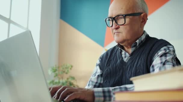 Αργή κίνηση του συνταξιούχου με τη χρήση υπολογιστή laptop πληκτρολογώντας στο γραφείο στο διαμέρισμα — Αρχείο Βίντεο