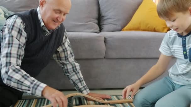 Homem velho e criança brincando com carros em casa desfrutando de jogo com brinquedos dentro de casa — Vídeo de Stock