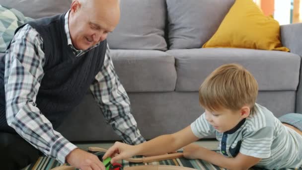 Niño feliz jugando coches de juguete con el abuelo amoroso moviendo autos juntos sonriendo — Vídeos de Stock