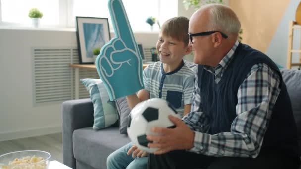 Veselý rodinný dědeček a vnuk sledující fotbal na TV jásání — Stock video