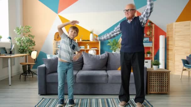 Sportieve familie grootvader en kleinzoon oefenen thuis samen praten — Stockvideo