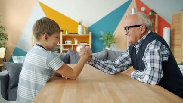 Zorgvuldige grootvader onderwijs jongen om te worstelen met plezier doen sport thuis — Stockvideo