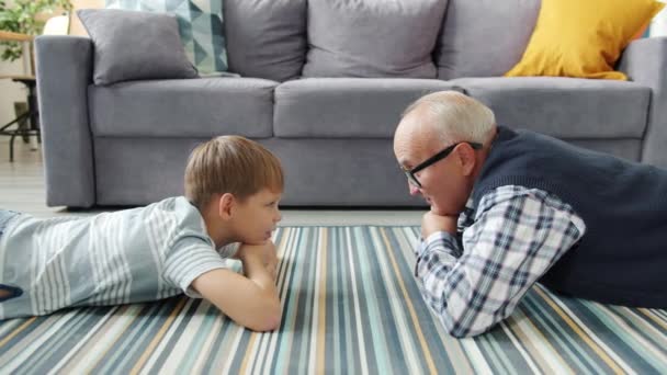 Grootvader praat met nieuwsgierig kind delen ervaring ontspannen op de verdieping — Stockvideo