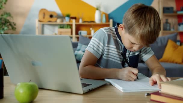 Cámara lenta del niño feliz usando el ordenador portátil para la escritura de la educación que hace la tarea — Vídeos de Stock