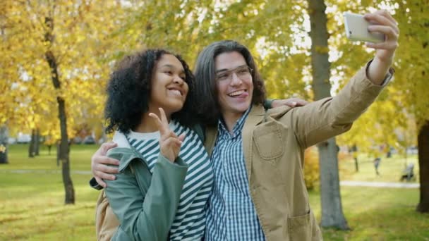 Mutlu çift, sonbahar parkında akıllı telefonuyla selfie çekiyor. — Stok video