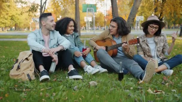 Young men and women playing the guitar singing enjoying autumn day in park — Stock Video