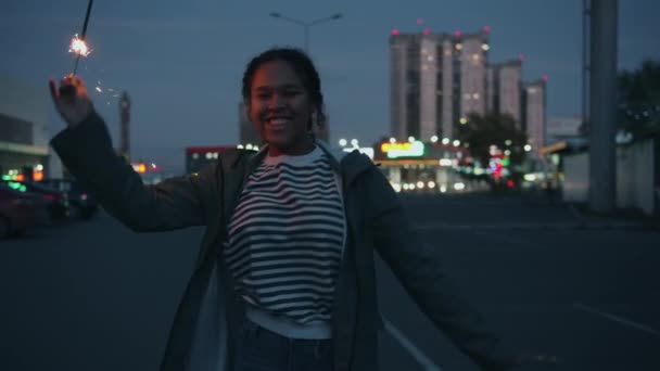 Jolie fille afro-américaine dansant en ville la nuit tenant la lumière du bengale à la main — Video