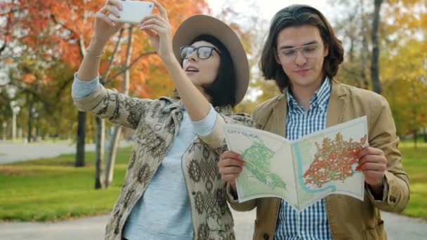 Tourists man and woman looking at map and taking pictures with smartphone outdoors — 비디오