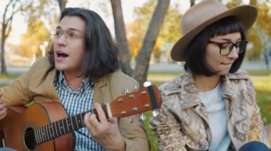 Şehir parkında gitar çalan yaratıcı gençlik portresi