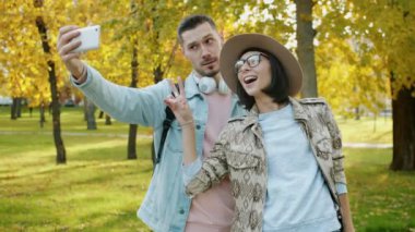 Parkta selfie çeken neşeli bir çiftin portresi.