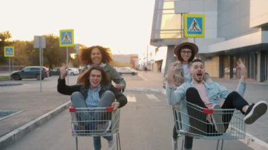 Kadınlar alışveriş arabalarını iterken erkeklerle beşlik çakıp gülüyorlar.