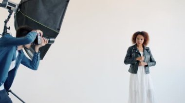 Stüdyoda kamera için karışık yarış modeli ve kamerayla fotoğraf çeken fotoğrafçı.