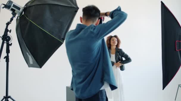 Modelo señora de raza mixta y fotógrafo trabajando en el estudio durante la sesión de fotos — Vídeos de Stock