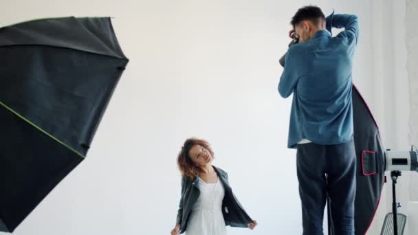 Vegyes verseny modell pózol a stúdióban, míg a férfi fotós fényképezőgéppel — Stock videók