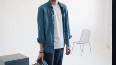 Stüdyoda elinde kamera olan yakışıklı bir adamın yavaş çekim portresi.