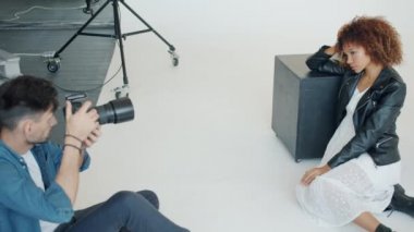 Modern stüdyoda başarılı bir fotoğrafçı genç bayanın fotoğrafını çekiyor.
