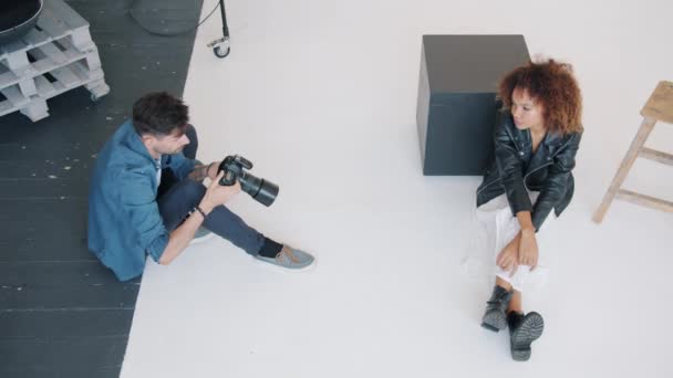 Vista de alto ángulo del fotógrafo tomando fotos de la modelo afroamericana en el estudio — Vídeos de Stock