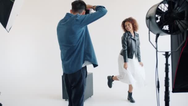 Cámara lenta de chica afroamericana posando para fotógrafo en el estudio — Vídeos de Stock