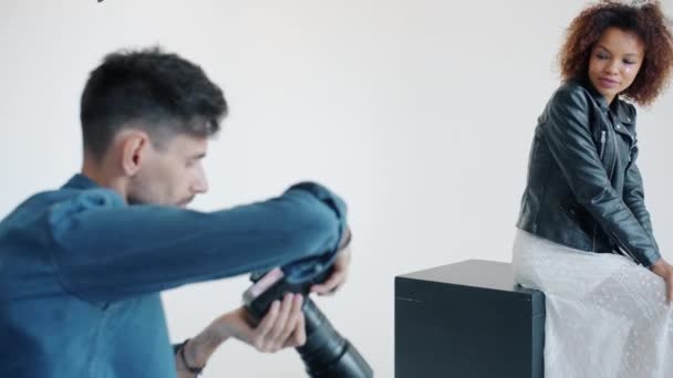 Charmantes Model posiert für Kamera, die mit Fotograf auf weißem Hintergrund arbeitet — Stockvideo