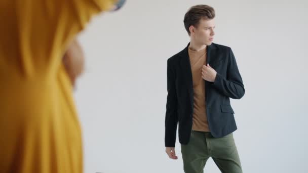 Modelo masculino atractivo posando usando ropa de moda en interiores en estudio fotográfico — Vídeos de Stock
