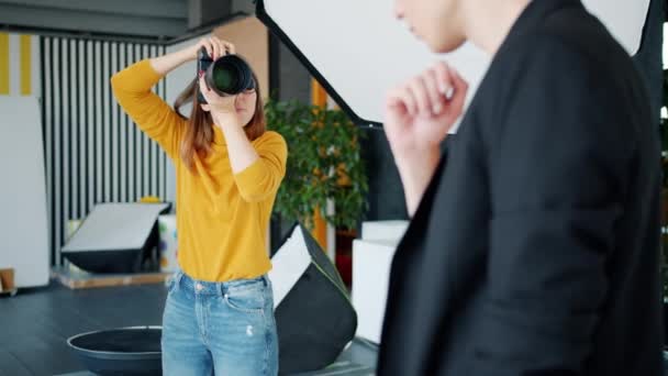 Mulher bonita fotógrafo tirar fotos de homem modelo posando em estúdio — Vídeo de Stock