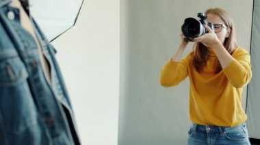 Stüdyoda modelle çalışan genç bir fotoğrafçı kamerayla konuşuyor.