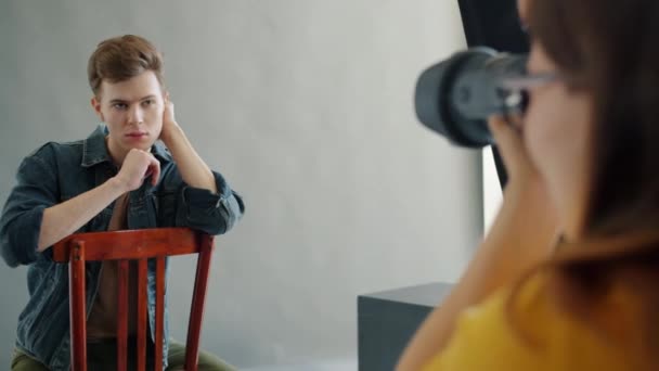 Bonito homem posando para câmera em estúdio trabalhando com fotógrafo feminino dentro de casa — Vídeo de Stock