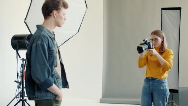 За кулисами модной фотосессии: фотограф показывает позиции мужского тела модели — стоковое видео