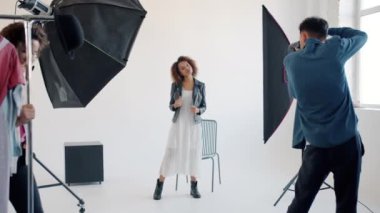 Stüdyoda genç modelin fotoğrafını çeken fotoğrafçı, sahne arkasında çalışan insanlar.